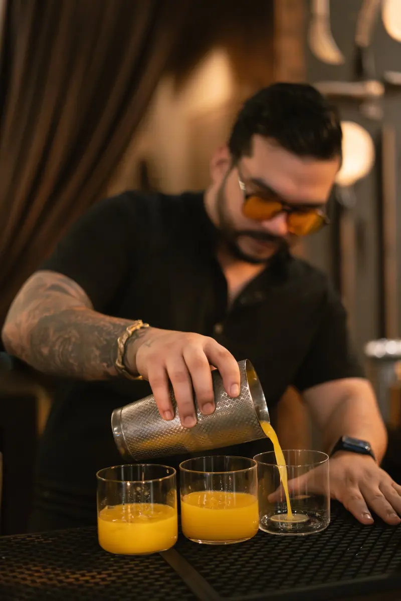 A bartender pouring cocktails at the bar